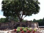 A stone sign for Lake Royale with a small waterfall, red and green landscaping, and a large tree in the background welcomes you near 131 Mohawk Drive in Louisburg.