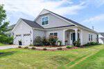 Charming single-story suburban house at 17 Pickerel Crest Way, Youngsville, featuring light gray siding, a dark roof, white trim, two-car garage, and a manicured lawn with shrubs and flowers under a partly cloudy blue sky.