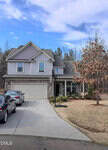 Two-story suburban house with gray siding, a double garage, and a basketball hoop in the driveway at 55 Nobleman Court, Franklinton. Two cars are parked outside, and there is a leafless tree on a brown lawn beside the house. A forested area provides a scenic backdrop.