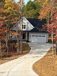 A two-story house with white siding, a dark roof, and a double garage sits at the end of a curved driveway at 3601 River Watch Lane in Franklinton, surrounded by autumn trees with colorful leaves.