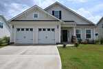A modern white house at 113 Sugarmaple Way in Youngsville features two garage doors, black shutters, a covered entryway, and a well-kept lawn under a cloudy sky.