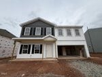 Newly constructed two-story house at 37 Plantation Drive, Youngsville, featuring striking black and white siding and an attached garage. The front yard remains bare dirt, and the home appears unfinished, with building materials still visible inside the garage.