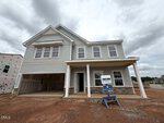 A newly built two-story house at 49 Plantation Drive, Youngsville, features gray siding, a covered front porch, and a "For Sale" sign in front. The garage door is open, and the yard has bare soil with no landscaping yet.