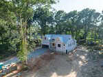 A large house under construction at 1039 Heather Lane in Wake Forest is surrounded by tall trees, with exposed framing and a partially completed roof. The home sits on a dirt lot with construction materials nearby, offering a glimpse of its impressive future amidst the natural beauty of the area.