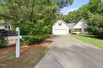 A white mailbox marked "35" stands by a curved driveway leading to a white house with a porch, surrounded by green trees and bushes on a sunny day at 35 Abbington Place in Youngsville.