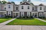 Charming two-story townhouse in Franklinton featuring gray siding and white trim, a manicured front lawn, neatly trimmed shrubs, and a covered entryway. A paved walkway leads from the sidewalk to the front door at 918 E Green Street.