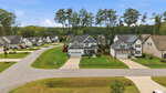 A suburban neighborhood in Youngsville with two modern two-story houses on well-kept lawns, concrete driveways, and a paved road in front. Trees and additional houses are visible in the background under a blue sky, creating an inviting setting at 15 Kathleen Court.