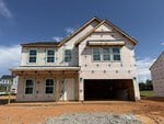 A two-story house under construction at 40 Plantation Drive, Youngsville, with exposed sheathing, visible window openings, and a large garage. The surrounding ground is bare dirt, and another building is visible on the right.