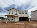 Two-story house under construction at 20 Silverbell Court, Youngsville, featuring exposed sheathing, uncovered windows, and a covered porch. Set on a dirt lot with other similar houses nearby under a partly cloudy sky.