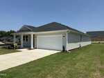 Single-story, white house with a black roof, two-car garage, and a "Sold" sign in the yard at 505 Purple Aster Street in Youngsville. The driveway and lawn are well-maintained, and the sky is clear and sunny.