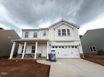 Two-story white house with a covered porch, double garage, and unfinished front yard under a cloudy sky. A real estate sign is placed near the driveway at 164 Sugarmaple Way in Youngsville.