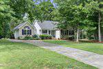 Single-story house with brick and siding exterior, arched windows, and a covered front porch. Nestled on 3637 Ashton Glen Lane in Oxford, it is surrounded by trees and greenery with a concrete driveway leading to the entrance.