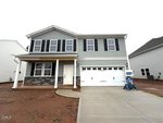 Two-story gray house with black shutters, a front porch with white columns, stone accents, and a two-car garage located at 160 Sugarmaple Way in Youngsville. The yard is bare dirt with no landscaping. A concrete driveway leads to the garage.