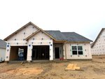 A single-story house under construction at 73 Moon Flower Walk in Youngsville, with wrap covering the exterior, a covered porch area, exposed timber, and construction materials scattered on bare ground in front.