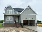 Two-story gray house with white trim, brick foundation, covered front porch, and double garage under construction at 45 Diamond Creek Drive in Zebulon. Some building materials are visible in the garage and driveway. The lawn is unfinished with patches of dirt.