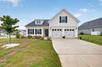 A white single-story suburban house at 44 Heartleaf Square, Youngsville, features a double garage, concrete driveway, small front porch, and a landscaped yard with a young tree and green grass under a clear sky.