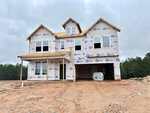 The two-story house at 117 Thompson Pond Way, Franklinton is under construction, wrapped in weatherproof sheeting with window openings and an unfinished porch. The ground is bare dirt, and a forested area is visible in the background under a cloudy sky.