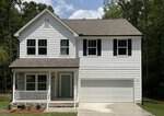 Charming two-story white house at 113 Ute Lane, Louisburg, featuring dark shutters, a covered front porch, light gray front door, two-car garage, and concrete driveway. The yard is adorned with small shrubs, while trees are visible in the background beneath a partly cloudy sky.