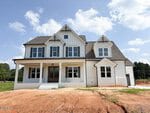 Two-story white house with multiple gables, large windows, and a covered front porch, set on a bare dirt lot with a concrete driveway at 160 Broadleaf Lane in Youngsville. The sky is mostly clear with a few clouds.