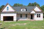 A partially constructed house at 20 Home Place Lane in Zebulon features exposed insulation wrap, a gabled roof, an attached two-car garage, three dormer windows, and a grassy yard in front. Wooden boards and construction materials are on the porch.