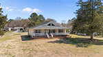 A single-story house at 35 Hummingbird Lane in Henderson features a large covered front porch, brick foundation, and light siding. It sits on a grassy lot with trees and neighboring homes in the background under a clear blue sky.