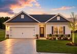 Single-story house with gray siding, stone accents, and a double garage at 45 Saddle Way in Youngsville, photographed at sunset. The front yard has manicured grass, a young tree, and landscaped flower beds near the lit front entrance.