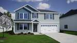 Two-story house with blue and light gray siding at 64 Mistflower Drive, Youngsville. Features include an attached two-car garage, a concrete driveway, a small front porch, and windows on both floors. A young tree and shrubs are planted in the front yard. The sky is partly cloudy.