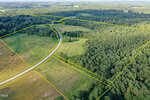 Aerial view of rural land with a winding road, grassy fields, and dense forested areas. Yellow lines outline the property boundaries of 60 Acres Timberlake Road, Louisburg. Trees cover the right side, while cleared land appears on the left and center.