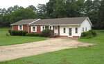 Charming single-story brick and white house with a gable roof, multiple windows, and a small front porch awaits you at 2635 W Lyon Station Road in Creedmoor. This inviting home sits on a large grassy lot adorned with shrubs and trees, while a wide concrete driveway leads to the welcoming front entrance.