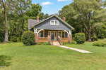 A gray, single-story house with white trim and a front porch sits on a large grassy yard at 280 Edwards Road in Henderson. Brick columns support the porch, and two large bushes flank the entrance. Tall trees are visible in the background.