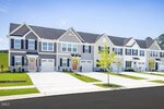 Row of modern two-story townhomes with attached garages, small front lawns, and young trees along a clean, wide driveway on a clear day in Youngsville. The homes at 362 Moose Meadow Way feature gray and white siding with black window shutters.