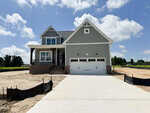 A newly constructed two-story gray house with a front porch, white trim, and a double garage sits on a lot with unfinished landscaping and a concrete driveway at 45 Diamond Creek Drive in Zebulon, all under a blue sky with scattered clouds.
