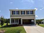 Nestled in the heart of Youngsville, this charming two-story suburban house at 195 Buckthorn Drive features beige siding, dark shutters, and a spacious double garage. The garage door is open, and the freshly landscaped lawn adds to its inviting curb appeal. The sky above is clear and sunny, creating a warm and welcoming atmosphere.
