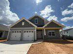 A newly constructed two-story house at 93 Moon Flower Walk in Youngsville features gray siding, white trim, two garage doors, a covered front porch, and an unfinished yard under a partly cloudy sky.