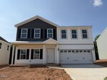 Two-story modern house located in Youngsville at 37 Plantation Drive, featuring a covered front porch, black shutters, and a double garage. The exterior showcases white siding with a dark upper section. The driveway and front yard appear unfinished, with bare ground.