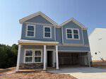 Charming two-story blue house with white trim and gray stone accents, located at 45 Plantation Drive in Youngsville. This home features a double garage, covered front porch, and several windows. The driveway and yard appear unfinished, with bare dirt surrounding the structure.
