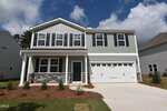 Two-story suburban house with gray siding, white trim, black shutters, a covered front porch, double garage, and landscaped yard with small shrubs and mulch located at 160 Sugarmaple Way in Youngsville. The sky is partly cloudy.
