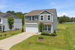 Two-story suburban house with gray siding, white trim, and attached two-car garage located on 40 Spotted Bee Way in Youngsville. Concrete driveway, small front yard with two young trees, and surrounding grassy lawn. Clear blue sky and neighboring houses are visible.