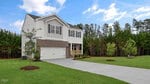 Beautiful two-story white house with brick accents, located at 45 Grazing Crop Court in charming Youngsville. This home features a double garage and a welcoming front porch. Enjoy the large concrete driveway and well-kept lawn with small trees, all set against a wooded area visible behind the property under a partly cloudy sky.