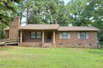 Charming single-story brick house in Franklinton, located at 115 Allen Avenue, featuring a small front porch, three front windows, and a wooden ramp on the left side. The grassy yard is shaded by tall trees, creating a welcoming and peaceful atmosphere.