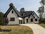 Modern two-story house at 5 Harvest View Way, Franklinton, featuring a white brick exterior with black trim and gray stone accents. The property boasts an attached double garage, wide driveway, and a landscaped front yard with small trees and shrubs. Mature trees are visible in the background.
