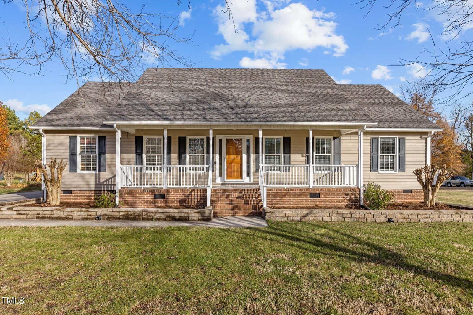 Nestled at 118 W Quailridge Road in Oxford, this charming one-story house boasts a gray roof and beige siding. Featuring a front porch with white railings and a wooden door, it is surrounded by a grassy lawn and leafless trees under a partly cloudy sky.