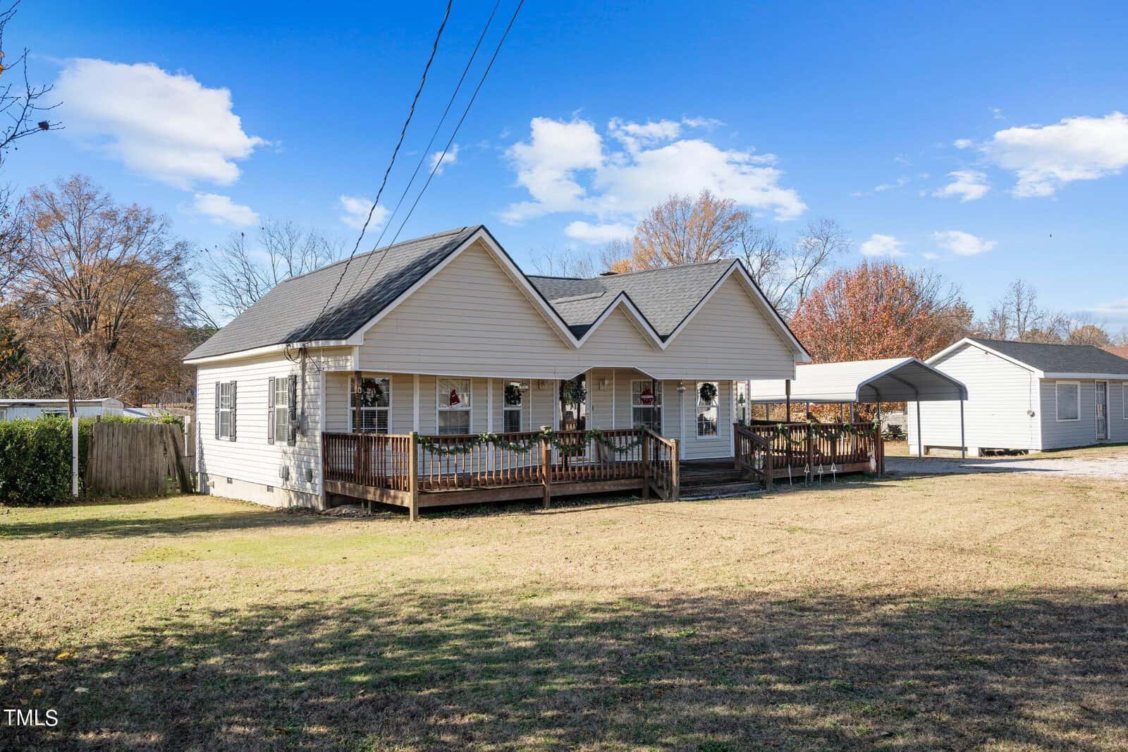 A single-story house with a gabled roof and a front porch, accompanied by a clear sky and surrounding grassy yard.