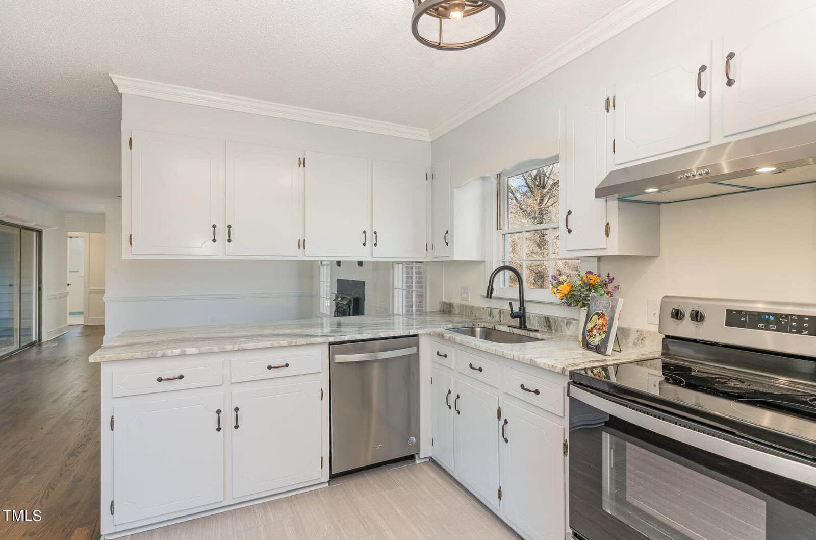A modern kitchen interior with white cabinetry, stainless steel appliances, and granite countertops.