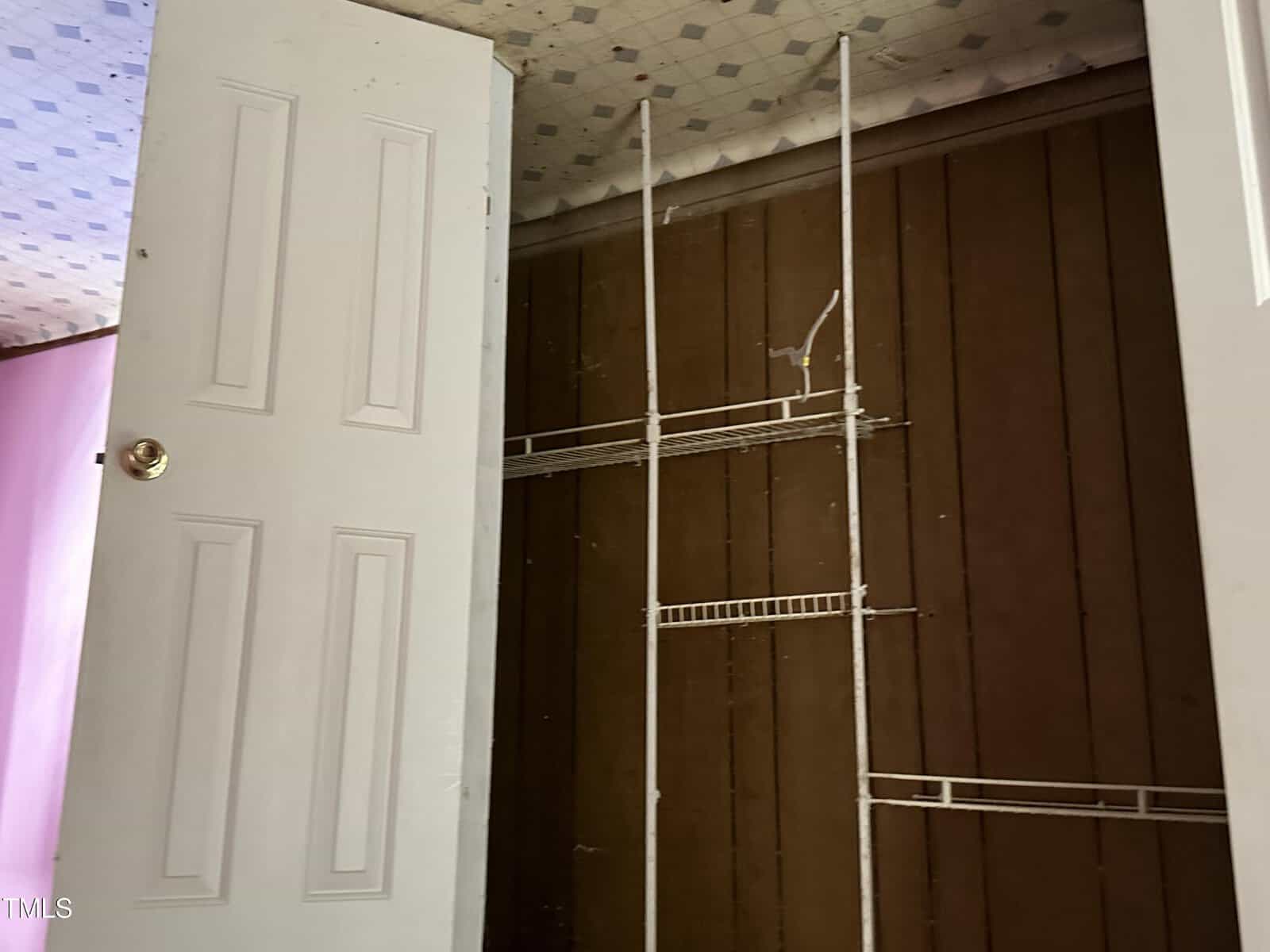 An interior room corner showing a white door on the left and a section of a wall on the right with an unfinished tile installation, featuring exposed thin-set mortar and tile spacers but no tiles.