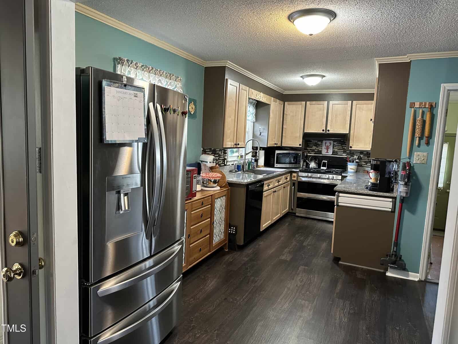 A well-utilized kitchen with stainless steel appliances, wooden cabinets, and cluttered countertops.