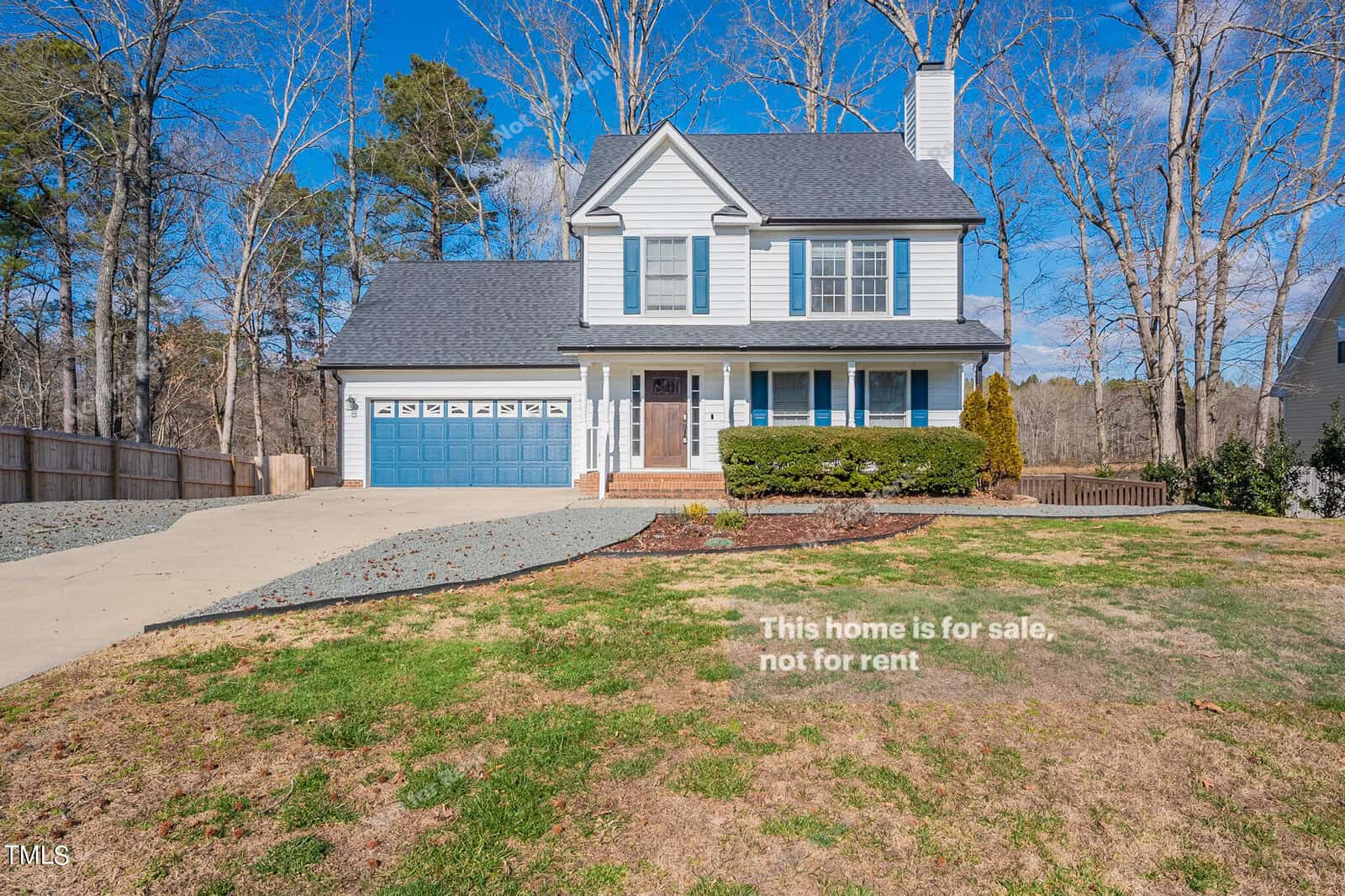 A charming two-story white house on 1649 Rogers Pointe Lane features a blue garage door and a chimney. Nestled in Creedmoor, it sits on a grassy lot with a driveway. A sign declares, "This home is for sale, not for rent." Surrounded by trees and offering a fenced backyard, it's an inviting residence.