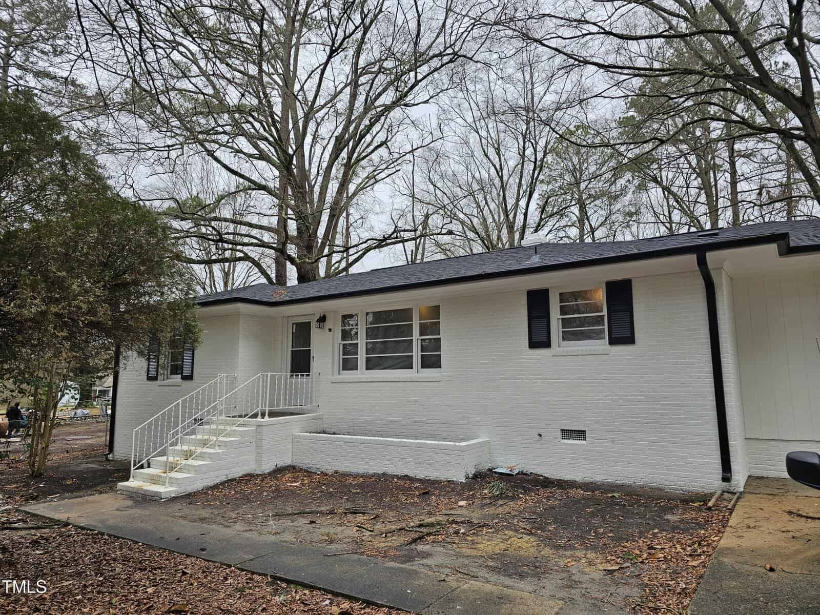 A white single-story brick house at 118 Wester Avenue, Henderson NC, with black trim, featuring multiple windows, a white front door, and a set of white stairs leading to the entrance.