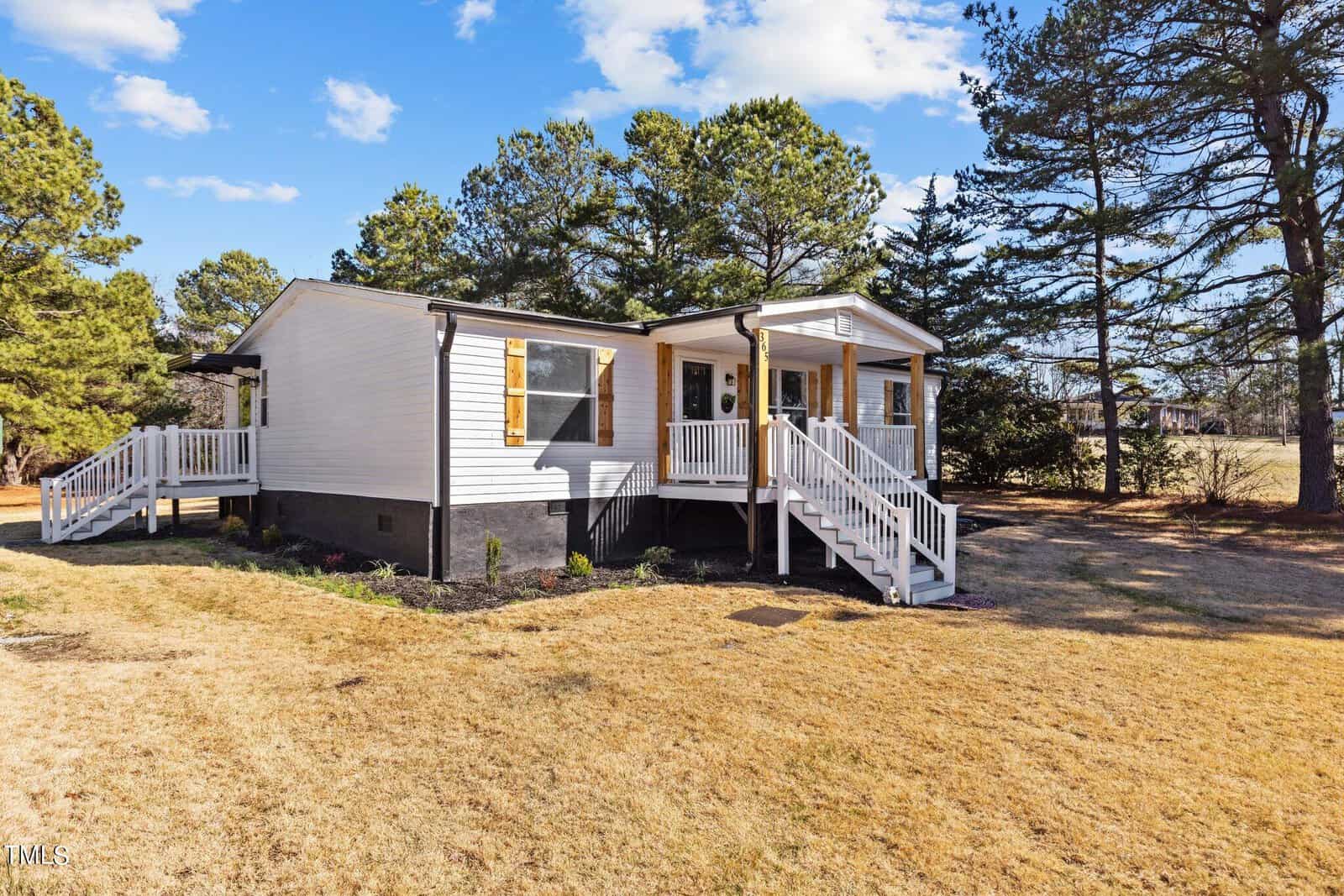 A single-story modular home at 365 Rev Henderson Road, Henderson NC, with white siding and contrasting black shutters, featuring an accessible front porch with white railings and a wheelchair ramp, situated in