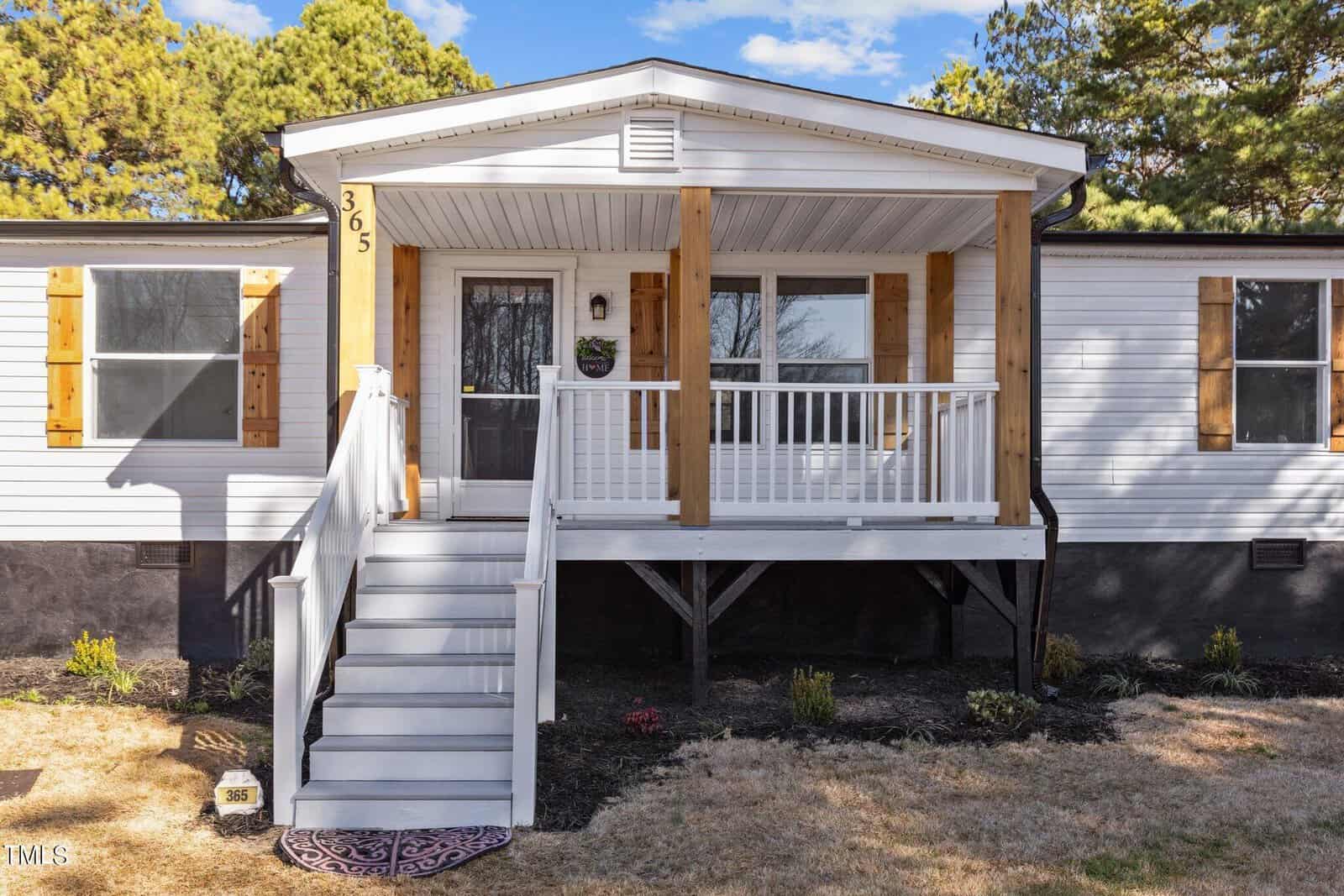 A single-story house with a small front porch, white railings, and steps leading to the entrance.